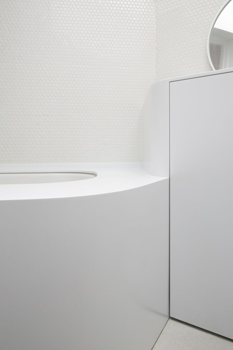 White curved Corian vanity unit and bath surround.
