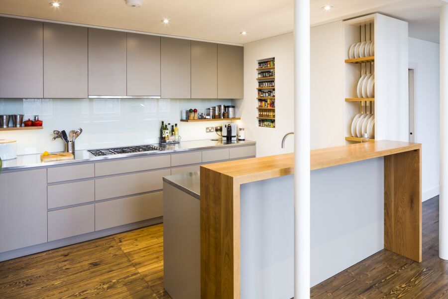 Modern kitchen with a mix of stainless steel and oak worktops, laminated plywood fronts and bespoke oak spice and plate racks..