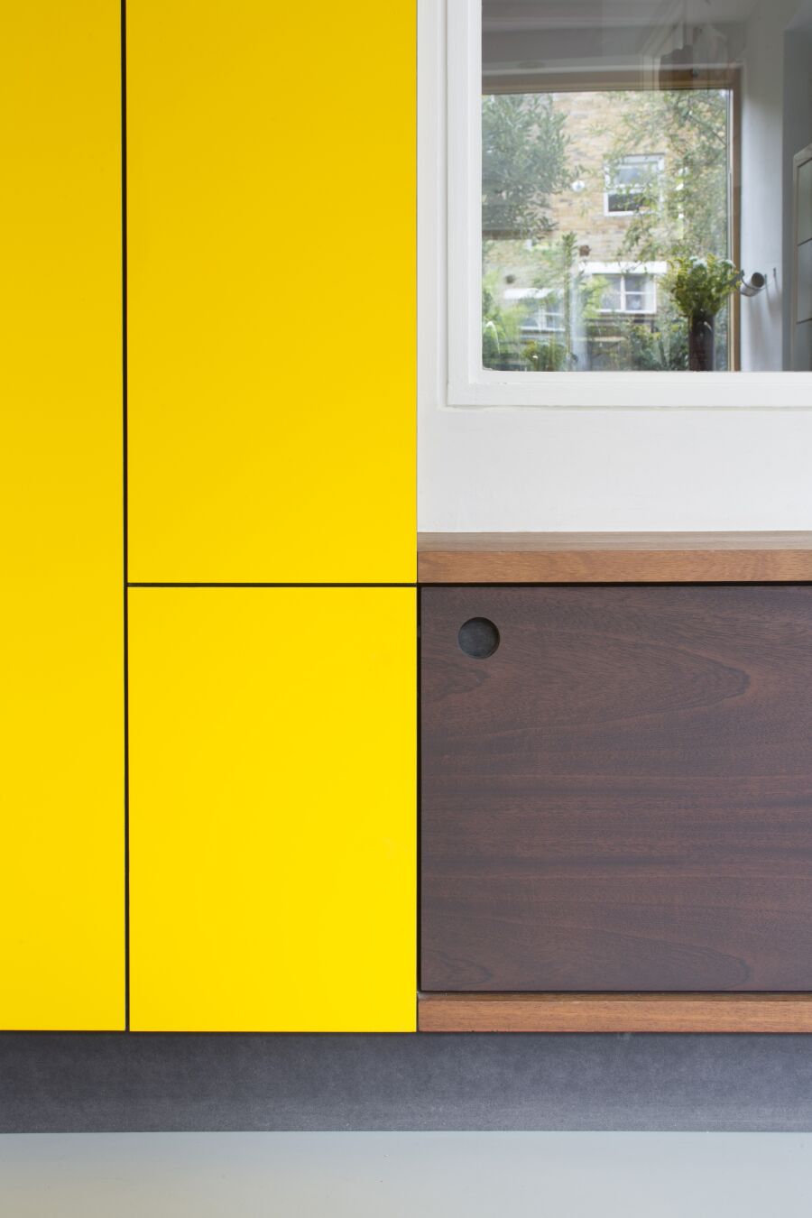 Kitchen with yellow laminate, stained Sapele on black Valchromat fronts and reclaimed solid Iroko bench seating..
